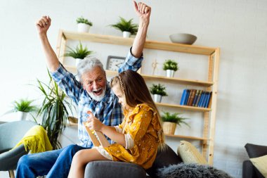 Mutlu büyükbaba evde küçük kız torunuyla gülmekten zevk alıyor.