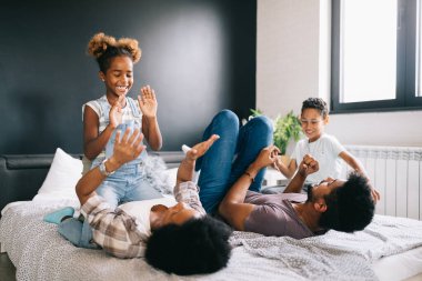 Mutlu bir aile evde bir yatakta oyun oynuyor ve eğleniyor.