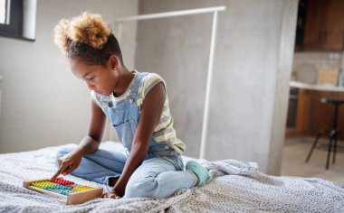 Şirin Afrikalı kız evde sayım çerçevesiyle oynuyor.