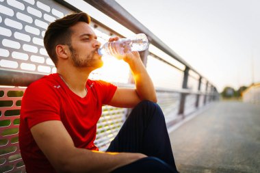 Yorgun adam koşucusu kardiyo çalışmasından sonra terliyor. Koşan yetişkin bir erkek mola veriyor.