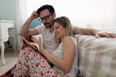 Genç çekici çift yatak odasında dijital tablet kullanma