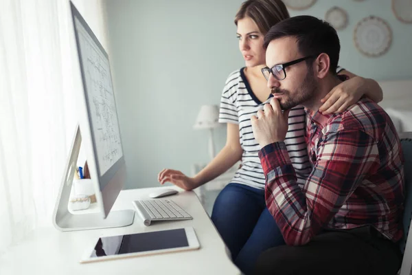 Young attractive couple of designers working on computer