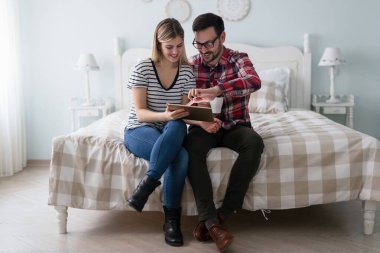 Mutlu genç çift yatak odasında dijital tablet kullanma