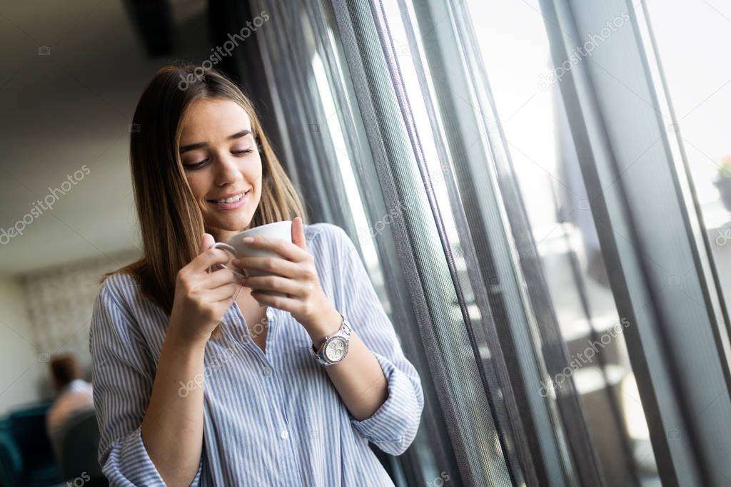 Beautiful young girl drinks coffee in the morning. Coffe cup. Window. Fashion