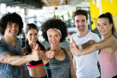 Spor salonunda birlikte egzersiz yapan bir grup mutlu arkadaş.