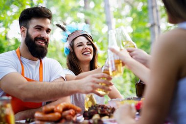 Bahçe barbeküsünde yemek yiyip kadeh kaldıran bir grup mutlu arkadaş. Evde gençlerin birlikte yemek yediği mutluluk kavramı.
