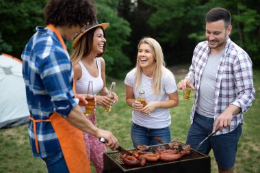 Arkadaşlar doğada barbekü yaparken eğleniyorlar.