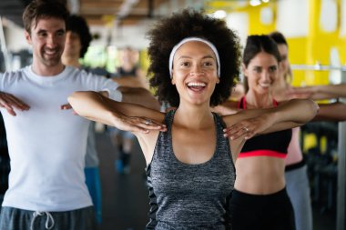 Spor salonunda birlikte egzersiz yapan bir grup mutlu arkadaş.