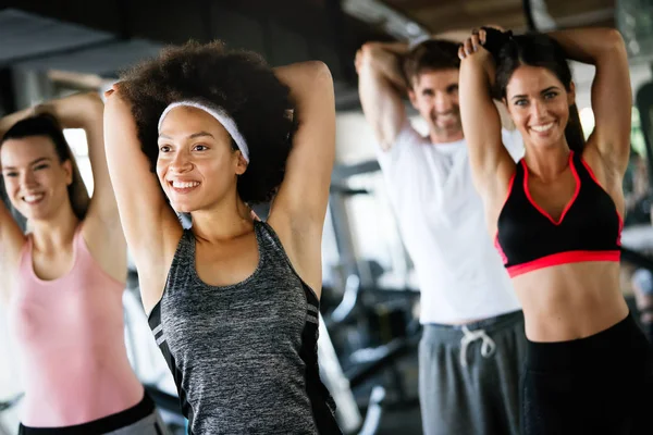 Diversity group of people training in a gym. Trainer and sportive fit persons exercising in a fitness class