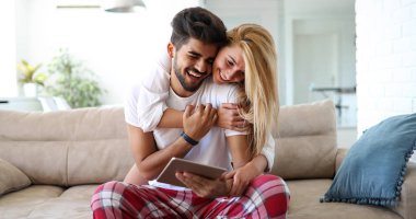 Şirin çift ile tablet evde oturma odasında kanepede rahatlatıcı