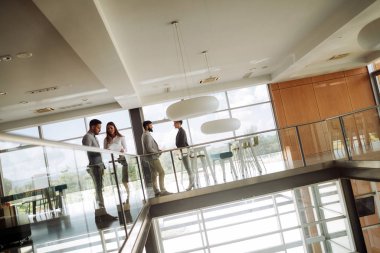 Modern ofis lobisinde iş adamları belgeler üzerinde tartışıyor..