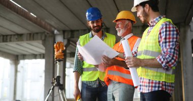 İnşaat mühendisleri ve mimarlardan oluşan bir ekip inşaat alanında çalışıyor.