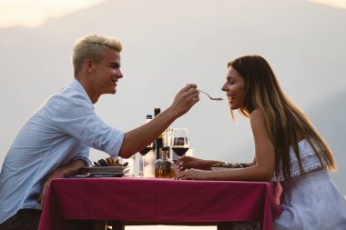 Mutlu genç çift yaz akşamında romantik bir akşam yemeği yiyor.
