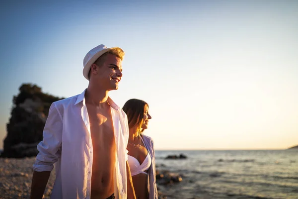 日没の夏休みにビーチでカップル 愛の中で美しい若者が歩く — ストック写真