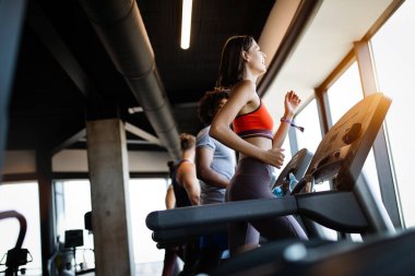 Spor salonunda koşu bandında koşan bir grup sağlıklı genç.