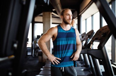 Spor salonunda koşu bandında koşan bir grup sağlıklı genç.