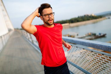 Yakışıklı genç adam köprüde koşuyor.