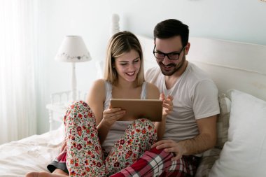 Genç çekici çift yatak odasında dijital tablet kullanma