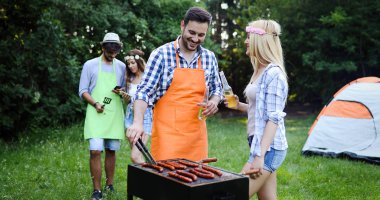 Yakışıklı mutlu erkek Barbekü açık havada arkadaşlar için hazırlanıyor