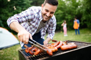 Boş zaman, yemek, insanlar ve tatil konsepti. Adam yaz partisinde barbekü ızgarasında et pişiriyor.