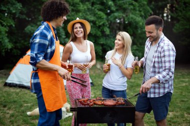 Küçük bir arkadaş grubu alkol içip barbekü partisinde yemek yiyor.
