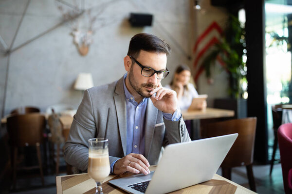 Portrait of a successful entrepreneur sitting at the cafe in front of a laptop.