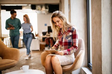 Güzel genç kadın dijital tableti çalışmak, okumak ve sörf yapmak için kullanıyor.