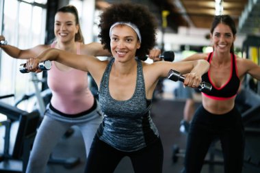 Güzel fit insanlar, spor salonunda birlikte egzersiz yapan arkadaşlar.
