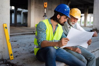 Mimarlar ve mühendislerden oluşan kendinden emin bir ekip inşaat alanında birlikte çalışıyor.
