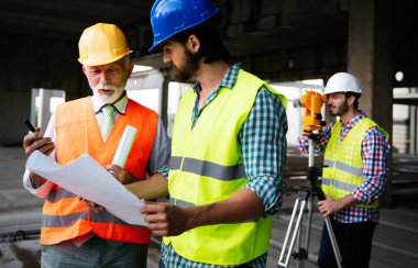 İnşaat mühendisleri ve mimarlardan oluşan bir ekip inşaat alanında çalışıyor.
