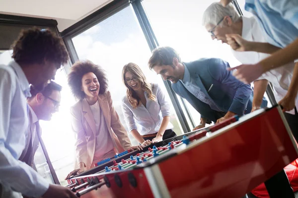 Business people having great time together.Colleagues playing table football in modern office.