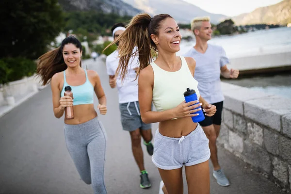 Group of young healthy fit people jogging and running outdoors in nature