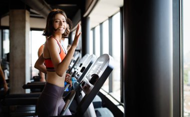 Spor salonunda koşu bandında koşan bir grup sağlıklı genç.