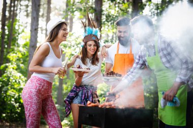 Arkadaşlar doğada barbekü yaparken eğleniyorlar.
