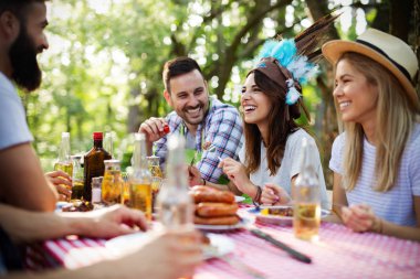 Bahçe barbeküsünde yemek yiyip kadeh kaldıran bir grup mutlu arkadaş. Evde gençlerin birlikte yemek yediği mutluluk kavramı.