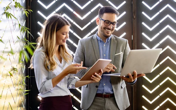 İş arkadaşları ofisteki dizüstü bilgisayara bakıp gülüyorlar.