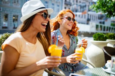 Arkadaşlar kafede harika vakit geçiriyor. Kızlar gülümseyen ve içme suyu ve zevk birlikte.