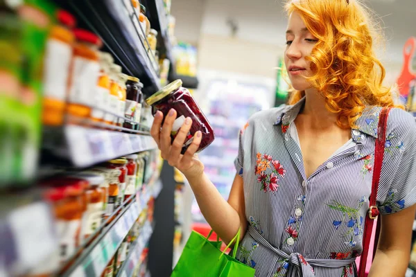 Happy young woman grocery shopping at the supermarket