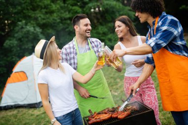 Arkadaşlar doğada barbekü yaparken eğleniyorlar.