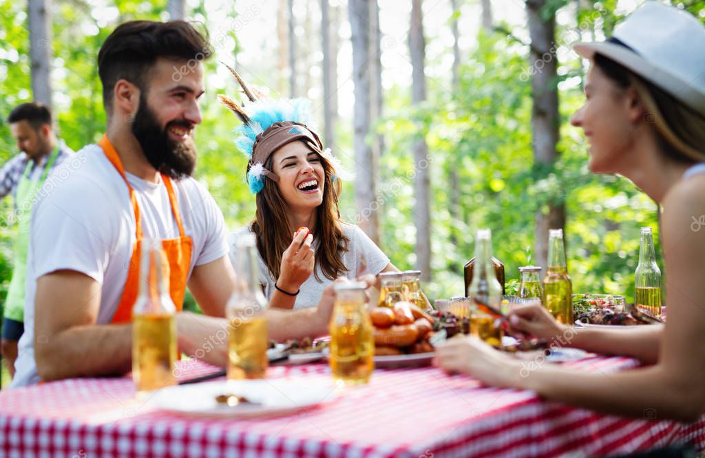 Small group of friends drinking alcohol and having a meal at barbecue party