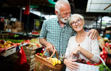 Sebzeli sepet bakkal dükkanında tutan gülümseyen kıdemli Çift