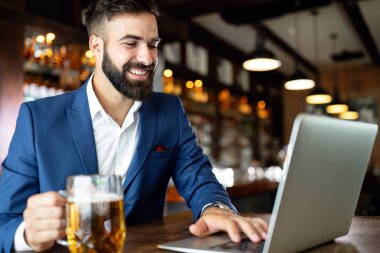 Restorandaki iş molasında dizüstü bilgisayar kullanan yakışıklı bir iş adamı.