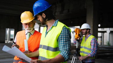 İnşaat mühendisleri ve mimarlardan oluşan bir ekip inşaat alanında çalışıyor.