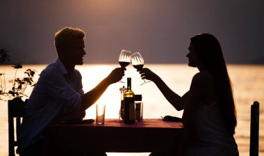 Genç çift sahilde romantik gün batımı akşam yemeği paylaşımı