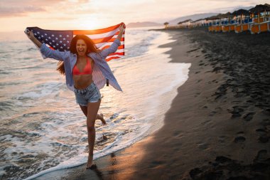 Mutlu kadın gülümseyip plajda koşarken bağımsızlık gününü kutluyor ve Amerika 'da özgürlüğün tadını çıkarıyor.