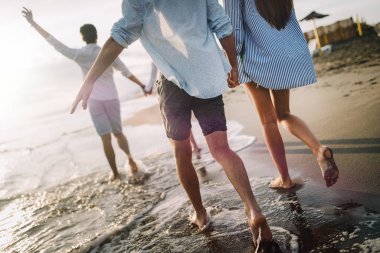 Mutlu mutlu çift gün batımında tropik bir plajda eğleniyor. Romantik tatil kavramı
