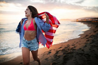 Mutlu kadın gülümseyip plajda koşarken bağımsızlık gününü kutluyor ve Amerika 'da özgürlüğün tadını çıkarıyor.