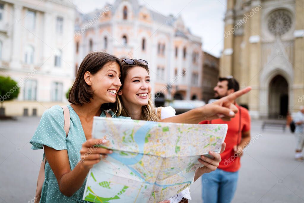 Happy traveling tourists friends sightseeing with map in hand