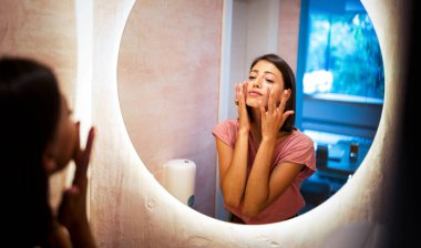 Yüzündeki kırışıklıklar yüzünden endişelenen bir kadının ayna yansıması.