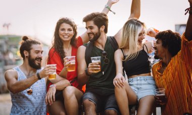 Bir grup mutlu arkadaş dışarıda eğleniyor, seyahat ediyor, gülümsüyor.